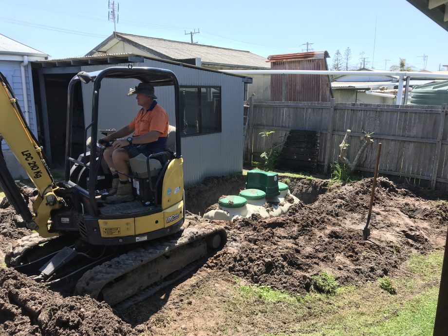 Compact home sewage treatment plant being installed in small backyard at Sandon River