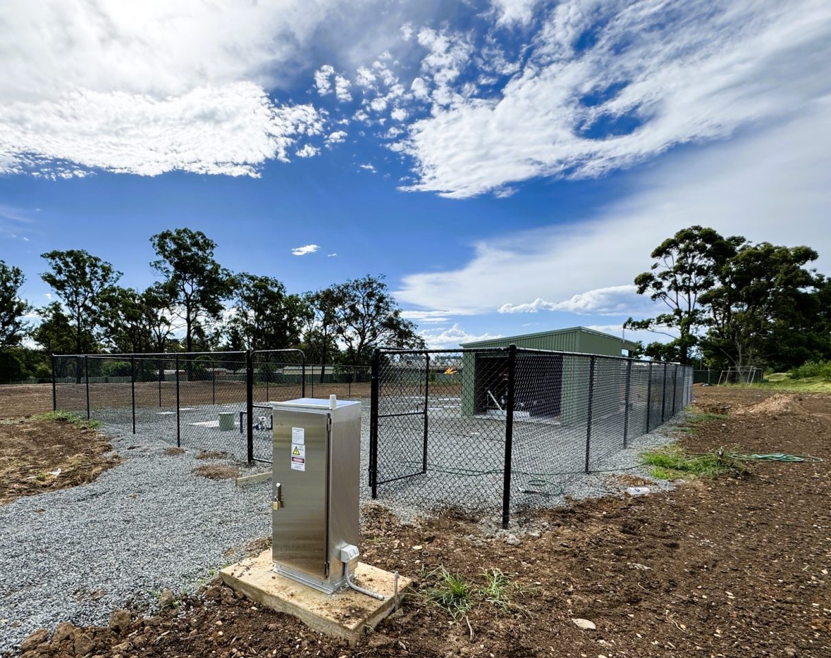 Fenced-off wastewater treatment facility in a rural setting.