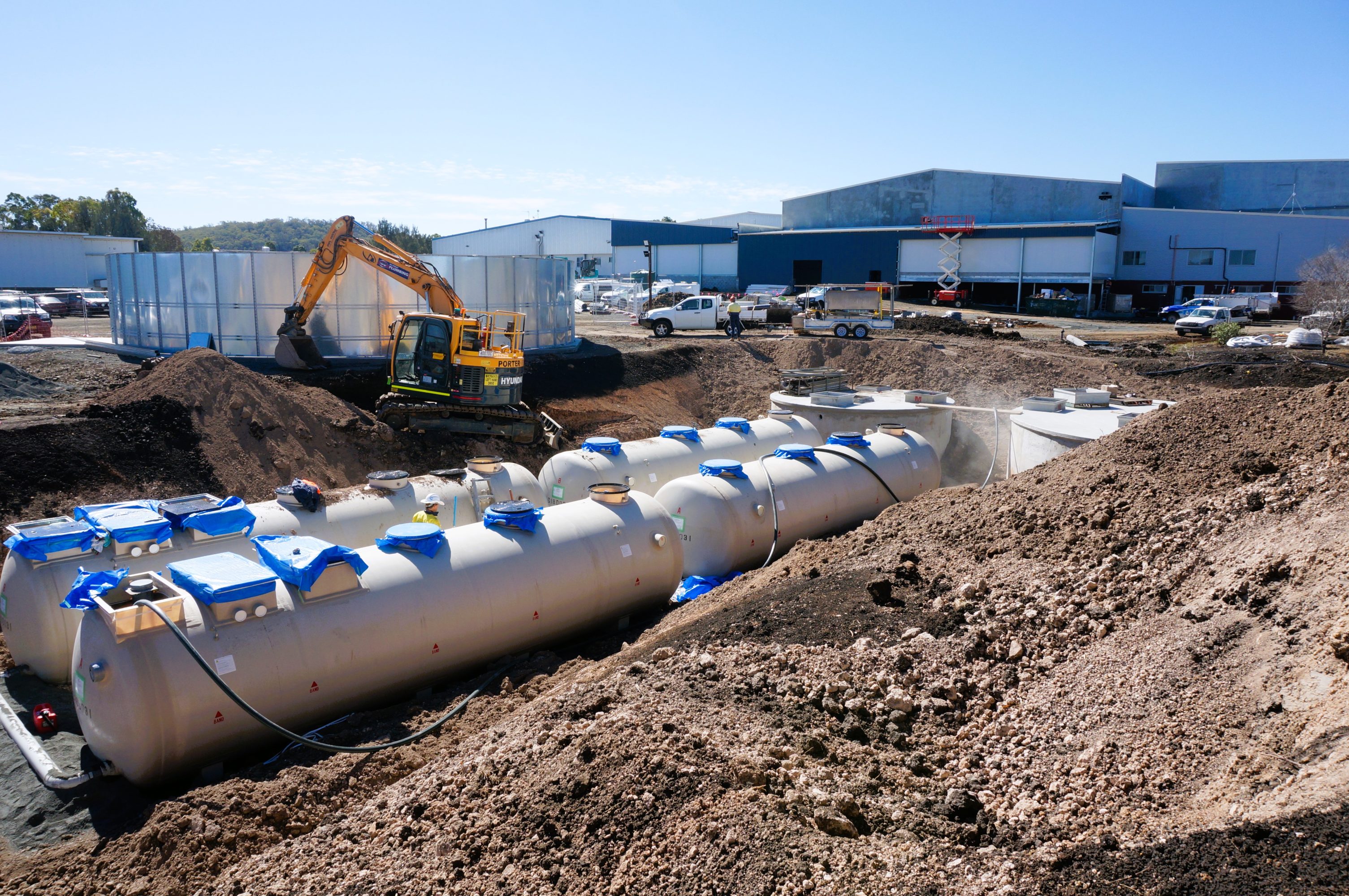 Wastewater infrastructure positioned in the dirt adjacent to a building.