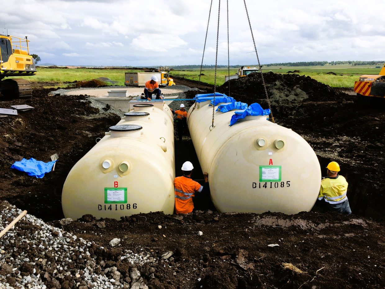 Large tanks being lowered into the ground, showcasing heavy machinery in action during installation.