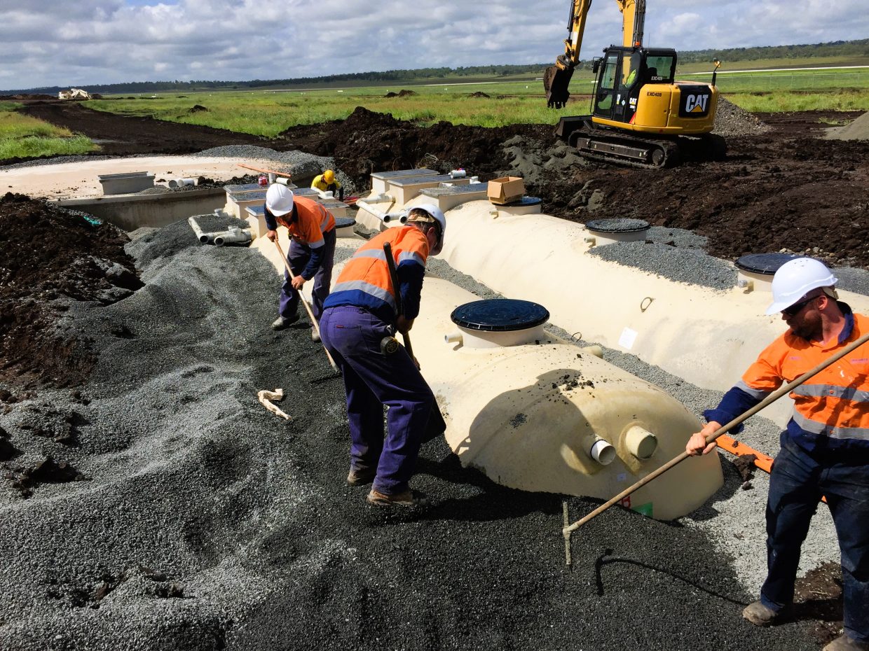 Several men engaged in work on a large tank, focusing on teamwork