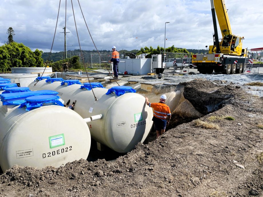 Workers lifting large tanks together, highlighting teamwork.