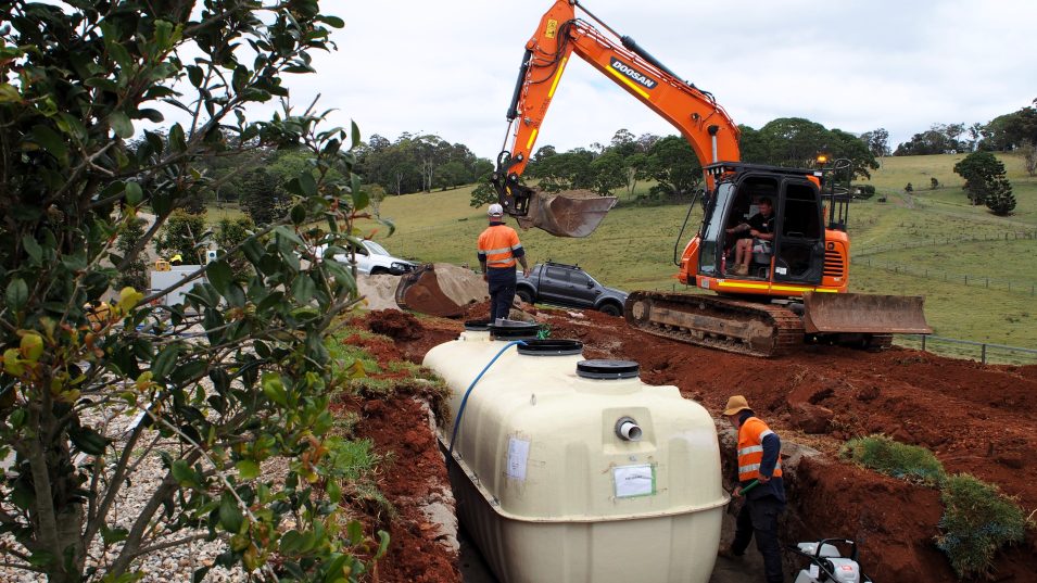 Construction workers engaged in the assembly of a wastewater tank, highlighting collaboration.