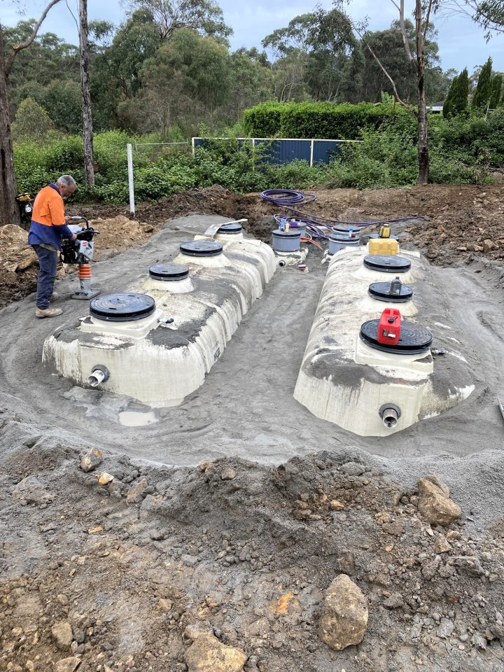 Working on a concrete tank, surrounded by dirt and construction materials.