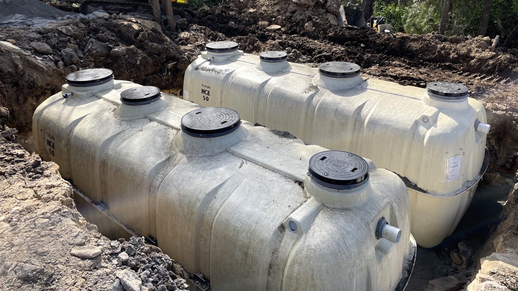 Sizable wastewater treatment tanks resting on a dirt ground, highlighting their industrial design in an outdoor setting.