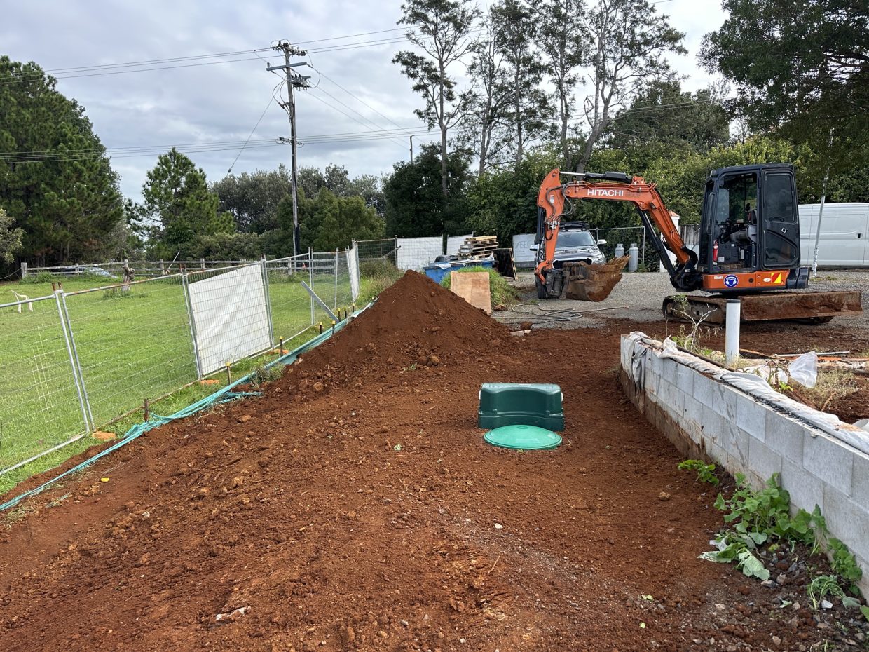 Sewage treatment system installed beside a retaining wall